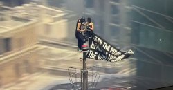 Two masked people climb to top of New York's Empire State Building as banner flown